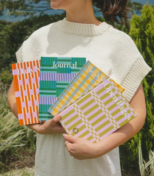Persona sosteniendo cuatro cuadernos coloridos de The Full Planner con diseños geométricos